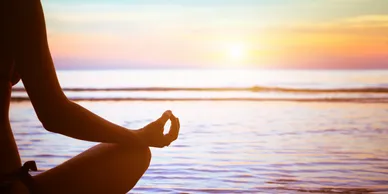 A person sitting in the lotus position on the beach